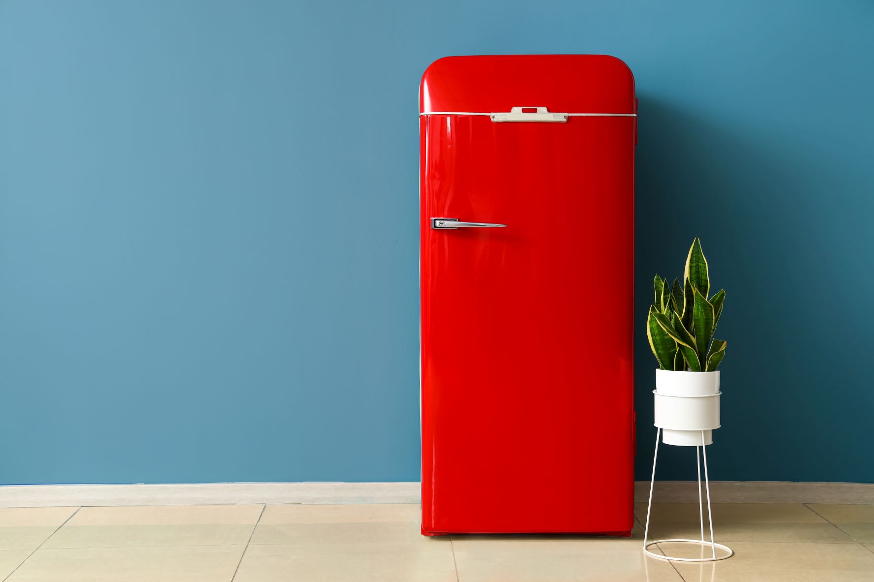 Ein roter Kühlschrank vor einer blauen Wand
